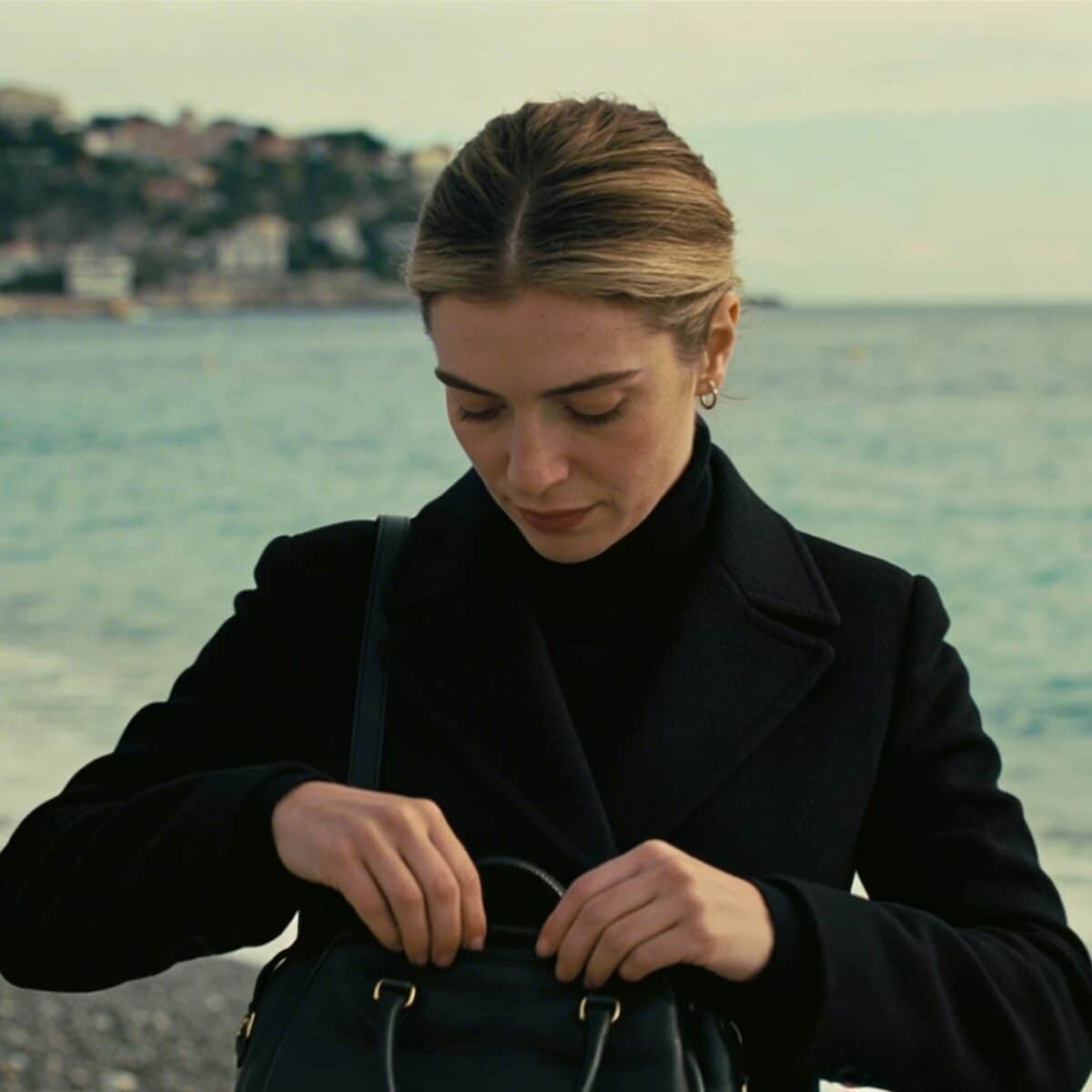 Femme debout sur plage de Nice ajustant sac devant mer