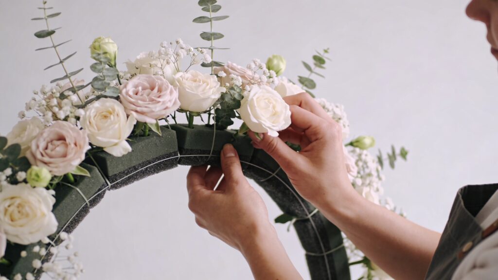 fleuriste ajustant arche florale mariage avec mousse