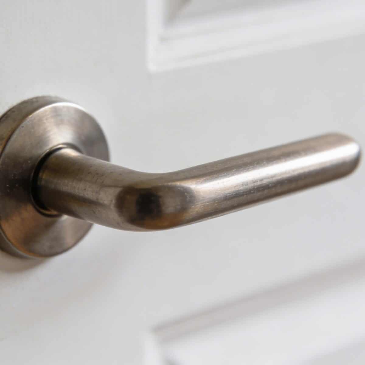Gros plan sur une poignée de porte metallique sur porte blanche