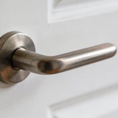 Gros plan sur une poignée de porte metallique sur porte blanche