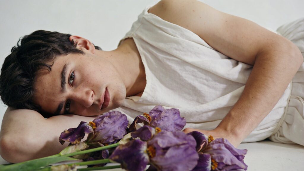 Jeune homme grec allonge pres de fleurs violettes