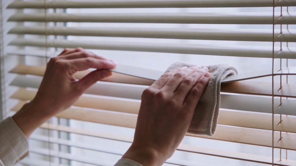 Personne depoussierant des stores venitiens fermes horizontalement