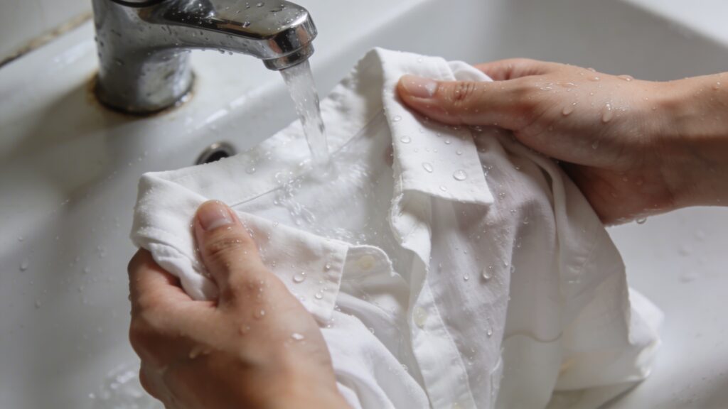 Personne rince chemise blanche delicatement sous robinet