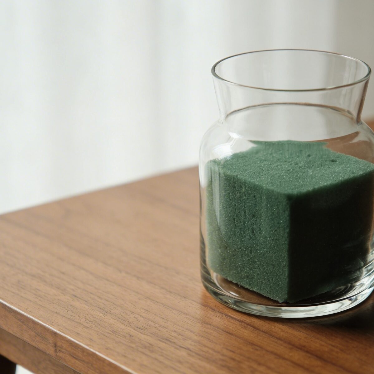 Vase transparent rempli de mousse florale verte sur table en bois